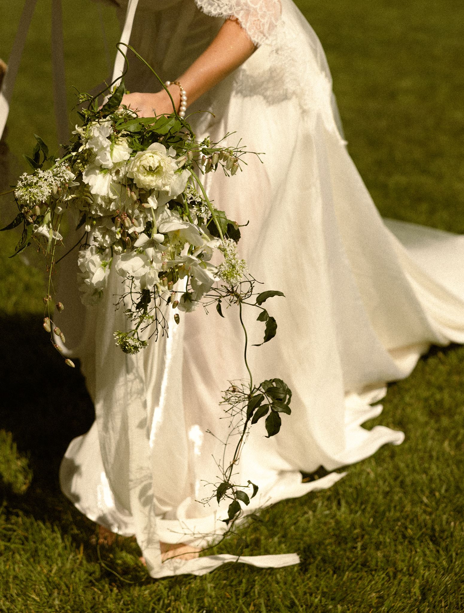 Bride carrying a cascading white and greenery bouquet