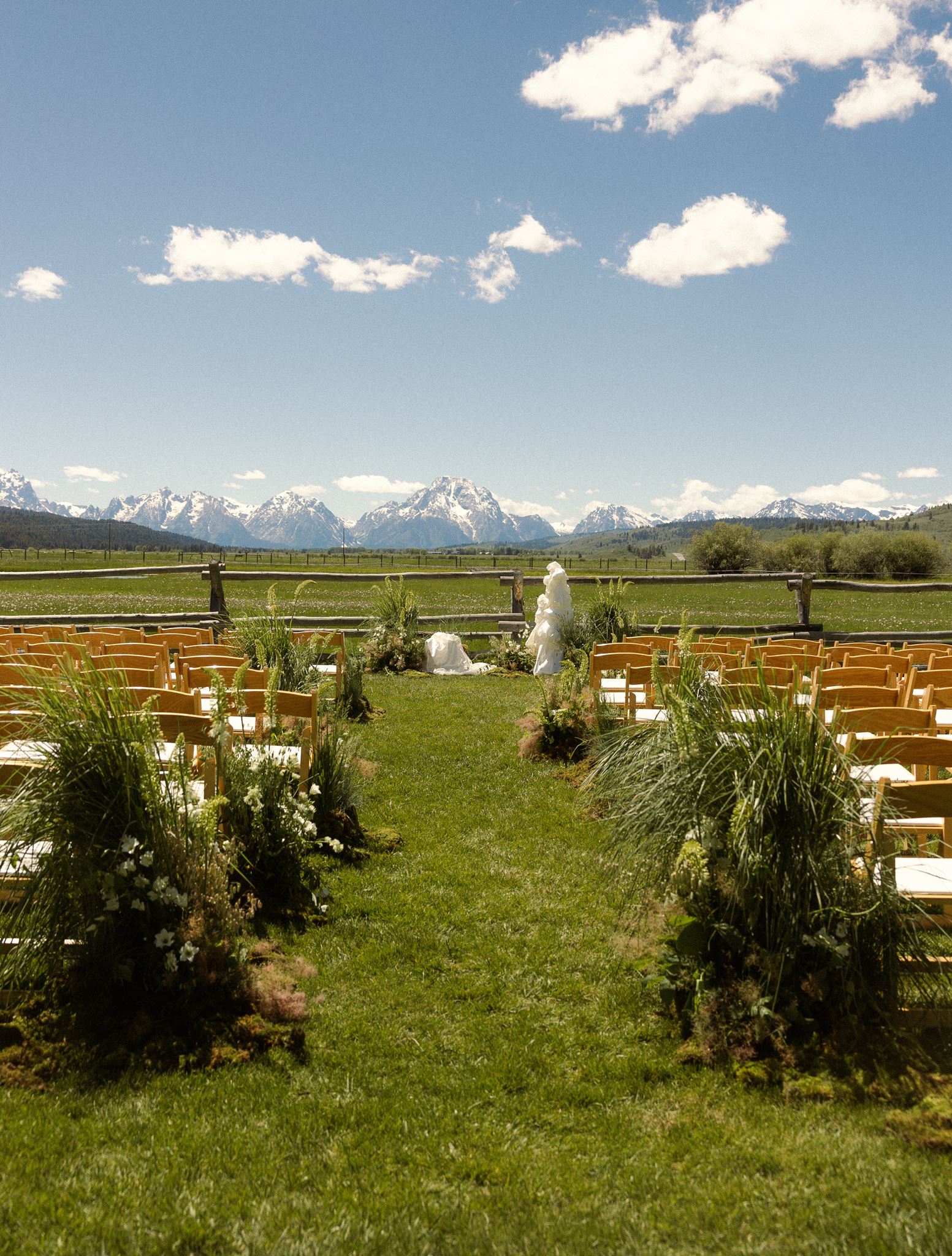 Ceremony aisle lined with wild greenery, Tetons in the background