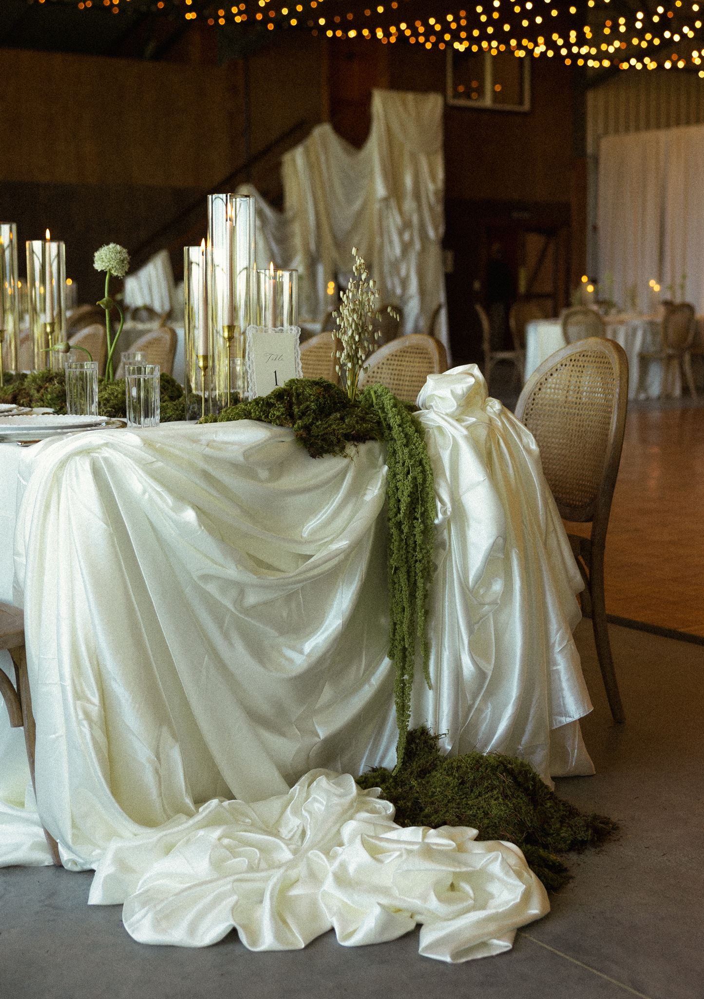 Reception table with draped ivory linen and string lights